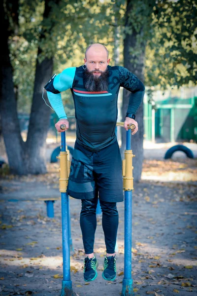 Hombre haciendo flexiones en barras paralelas - foto de stock