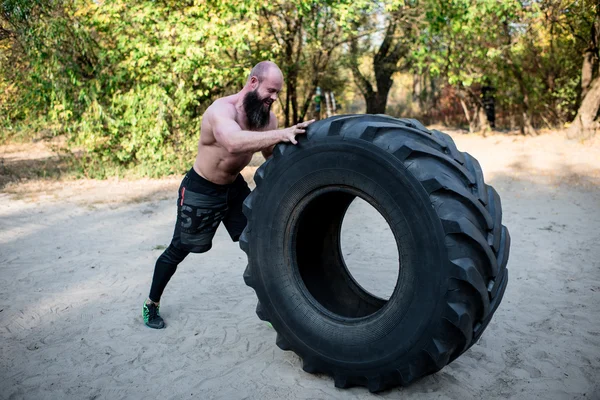 Homem muscular trabalhando com pneu pesado — Fotografia de Stock