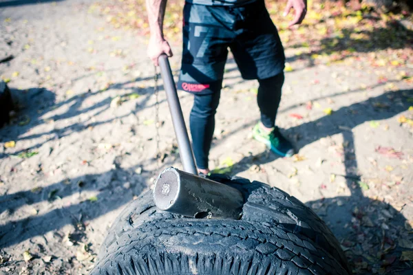 Man exercising with hammer and tire — Stock Photo