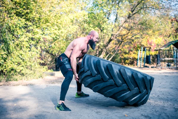 Homme fort travaillant avec un pneu de tracteur — Photo de stock