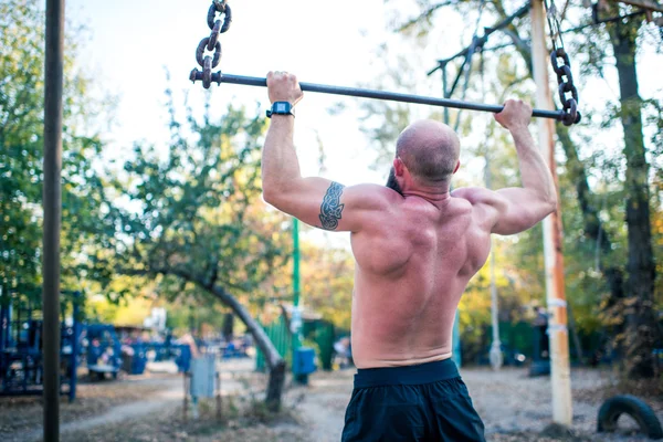 Man doing chin-ups in outdoor gym — Stock Photo