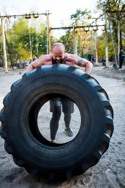 Hombre levantando neumático pesado - foto de stock