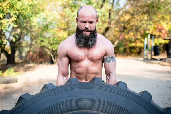 Man lifting a large tractor tire — Stock Photo