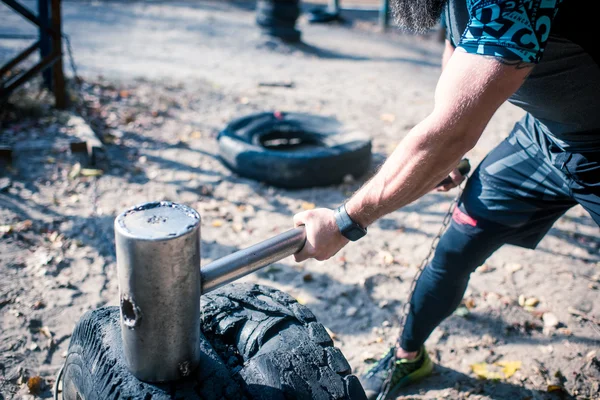 Mann schlägt mit Vorschlaghammer auf Reifen ein — Stockfoto