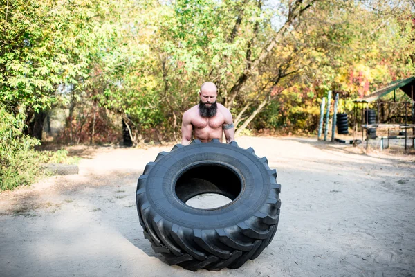 Hombre levantando un neumático tractor grande - foto de stock