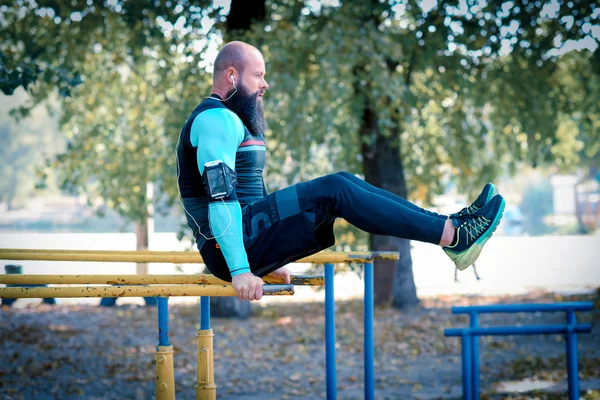 Homme barbu musclé sur des barres parallèles — Photo de stock