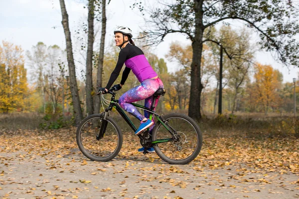 Mujer ciclismo en el parque de otoño — Foto de Stock