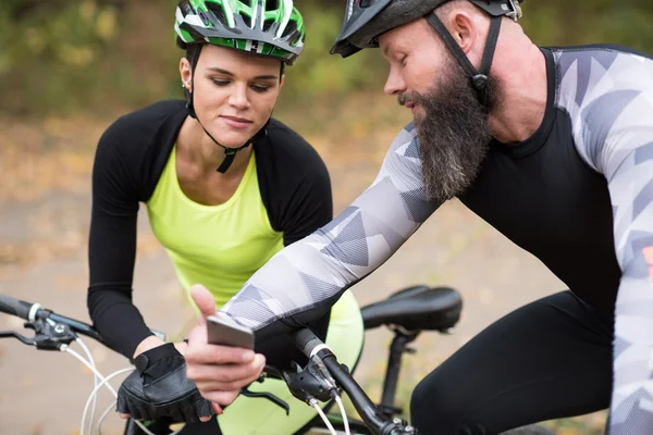 Man cyclist showin smartphone to girl — Free Stock Photo