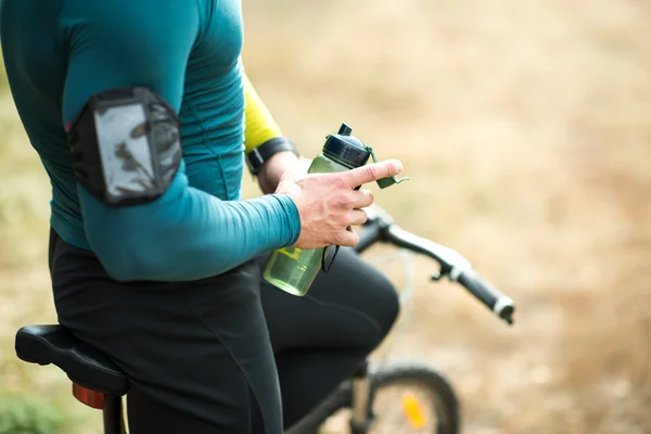 Cyclist holding bottle of water — Stock Photo, Image