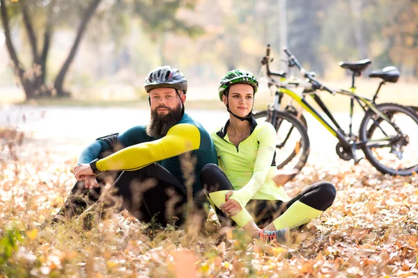 Ciclistas descansando en el césped seco de otoño —  Fotos de Stock