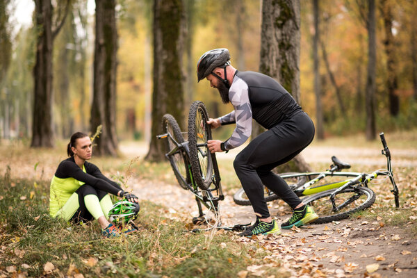 Человек ремонтирует велосипед в парке
