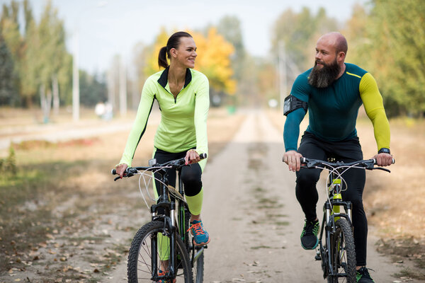 Smiling couple cycling in park 