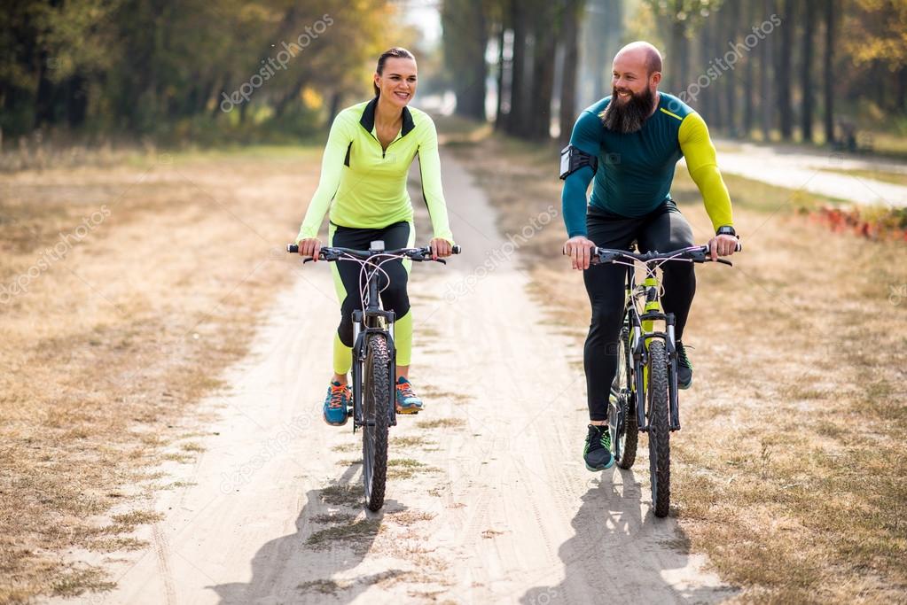 Smiling couple cycling in park 