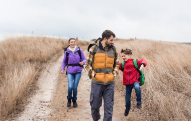 Happy family with backpacks walking clipart
