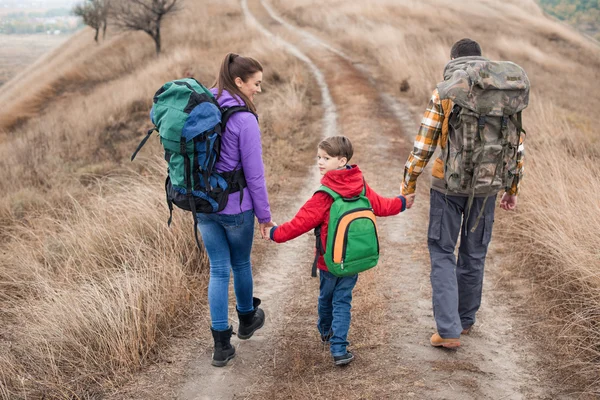 Family with backpacks walking on rural path — Stock Photo, Image