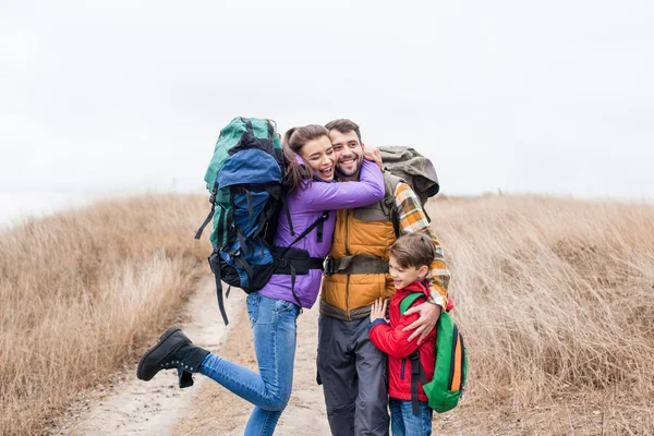 Happy family with backpacks hugging — Stock Photo, Image