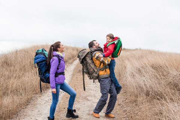 Happy family with backpacks hugging 