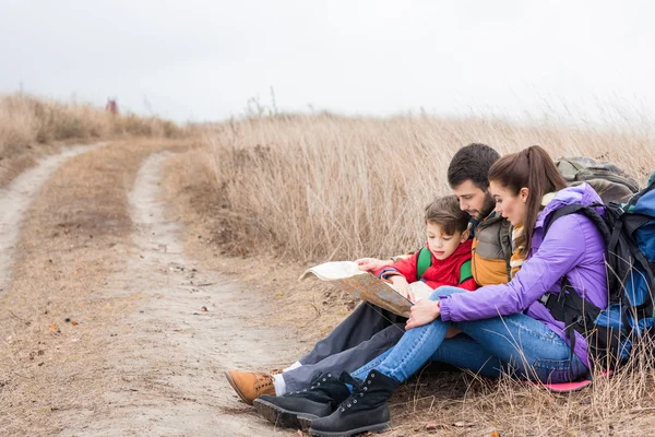 Familia con mochilas mirando el mapa — Foto de Stock