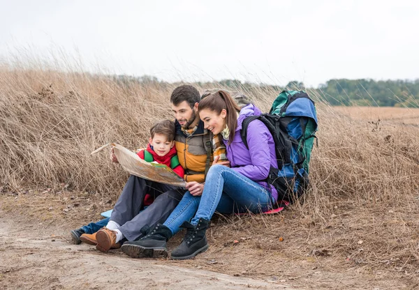 Family with backpacks looking at map — Stock Photo, Image