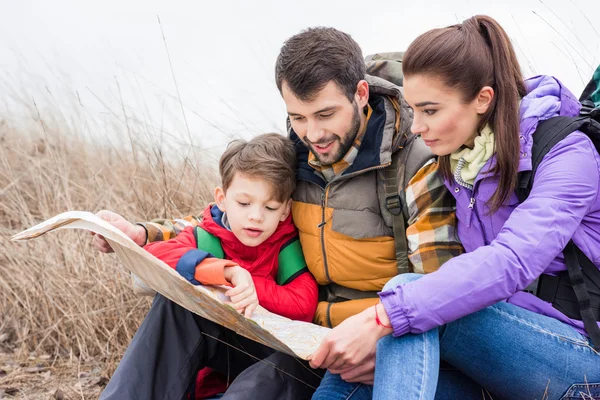 Family with backpacks looking at map — Stock Photo, Image