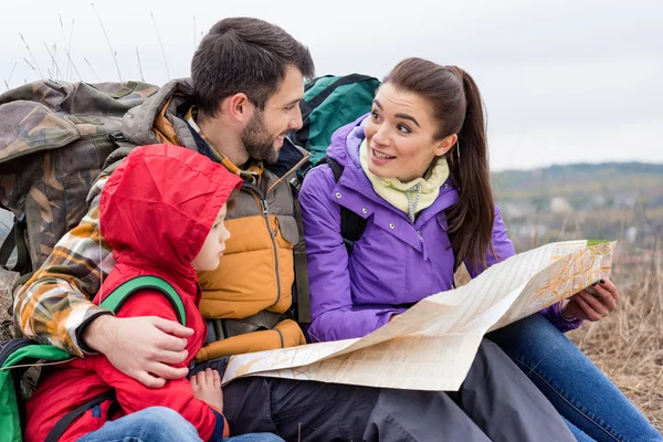 Family with backpacks looking at map — Stock Photo, Image