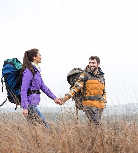 Otların arasında yürüyüş sırt çantaları ile gülümseyen Çift 