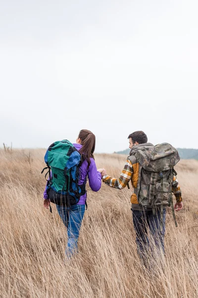 A fiatal pár, hátizsákok, séta a vidéken — Stock Fotó