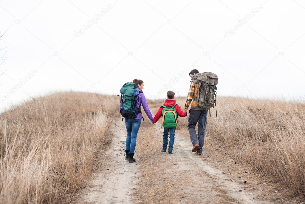 Family with backpacks walking on rural path