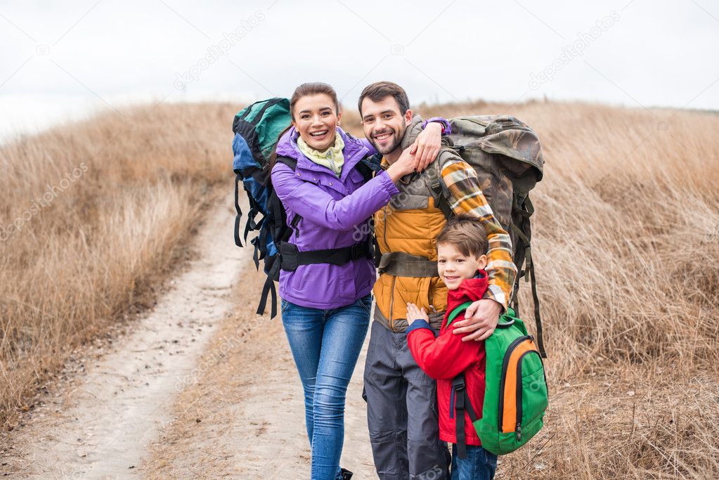 Happy family with backpacks hugging 