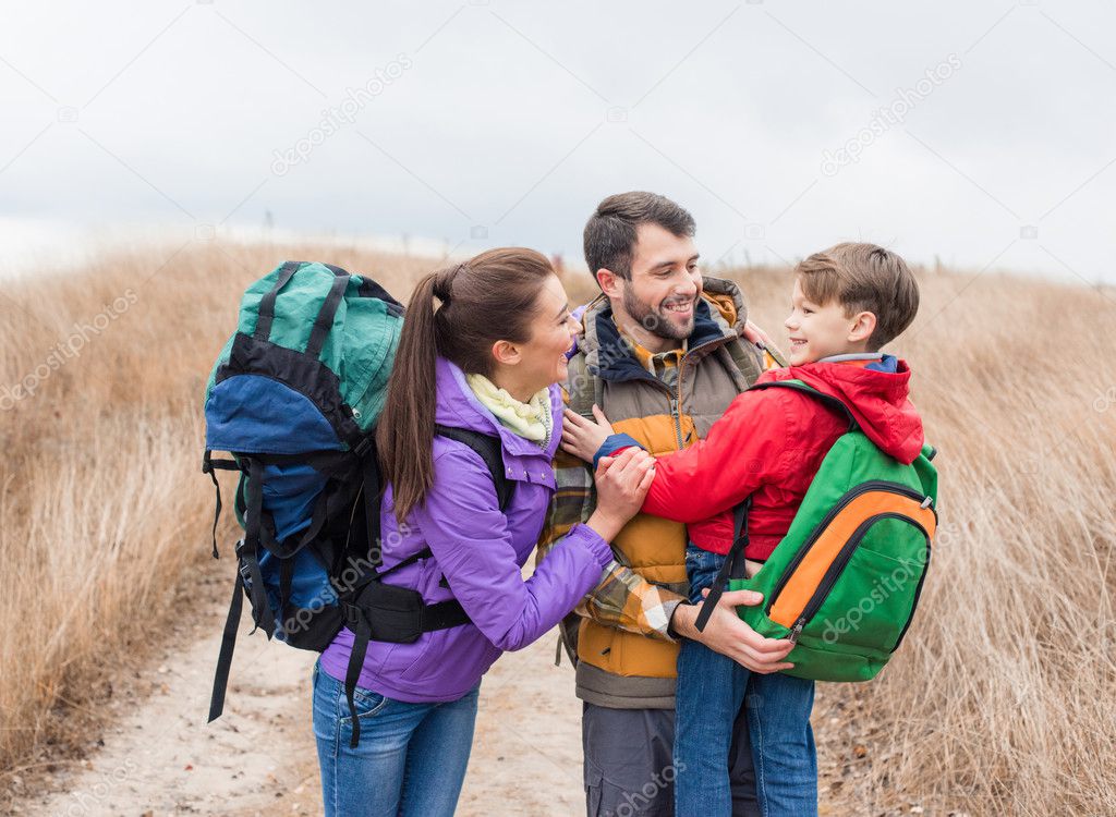 Happy family with backpacks hugging 