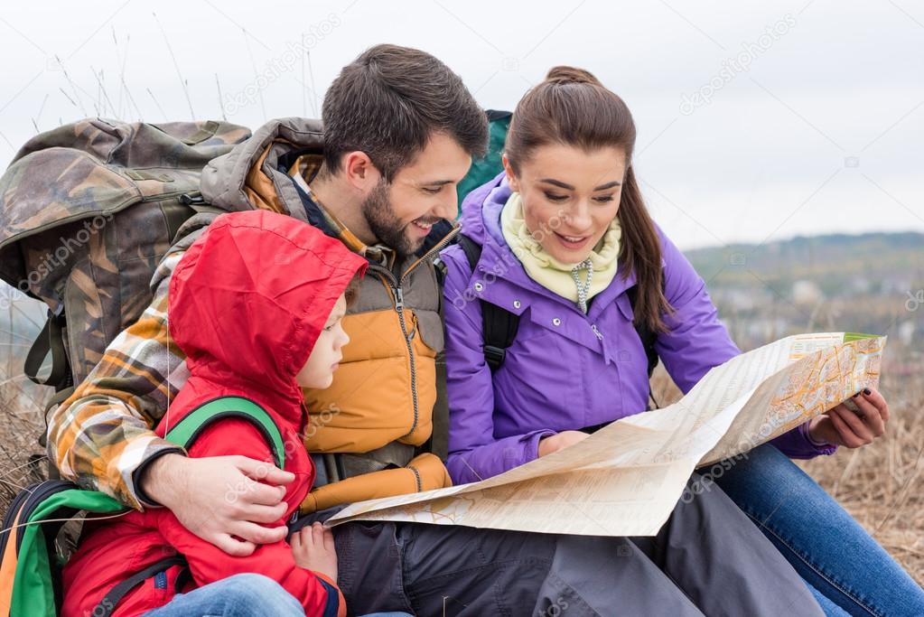 Family with backpacks looking at map