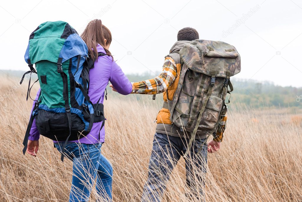 Young couple with backpacks walking in countryside