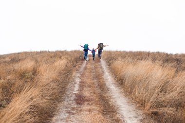 Family with backpacks running on rural path clipart