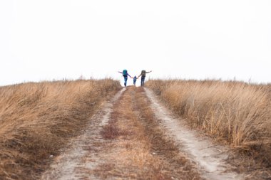 Family with backpacks running on rural path clipart