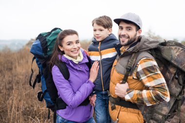 Sırt çantaları ile gülümseyen aile