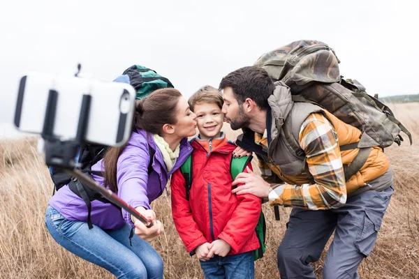Happy family with backpacks taking selfie — Stock fotografie