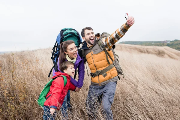 Família feliz com mochilas fazendo selfie — Fotografia de Stock
