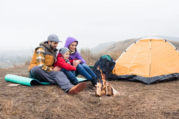 Glückliche Familie schaut auf brennendes Feuer — Stockfoto