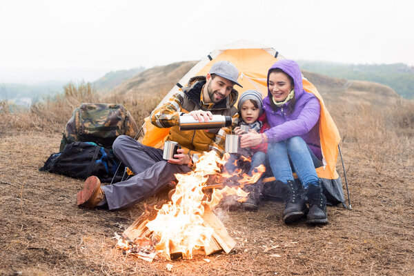 Family drinking tea near burning fire