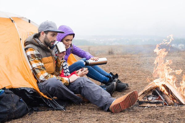 Family drinking tea near burning fire