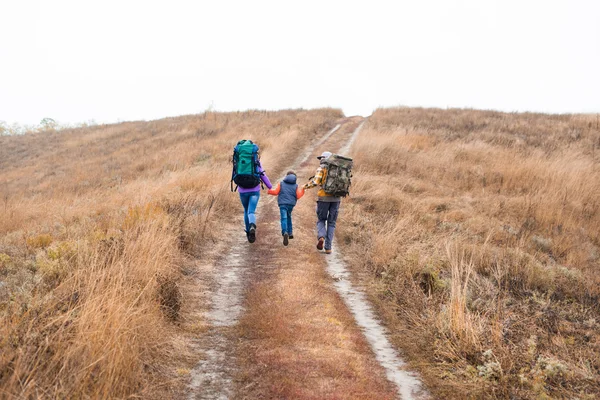 Family with backpacks running on rural path — Stockfoto