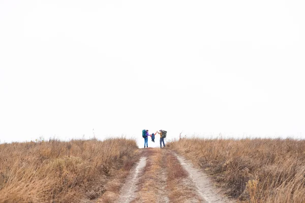 Family with backpacks running on rural path — ストック写真