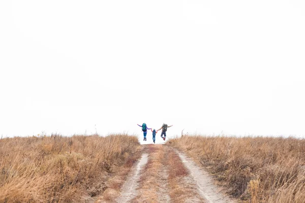 Família com mochilas correndo no caminho rural — Fotografia de Stock