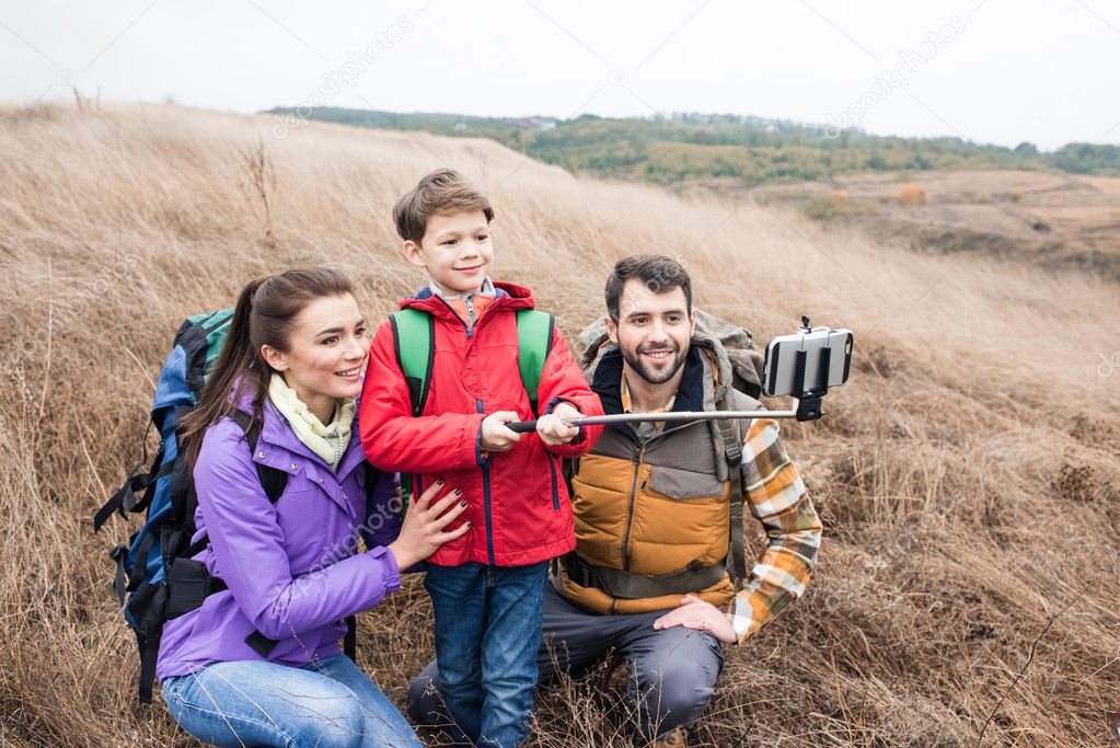 Happy family with backpacks taking selfie