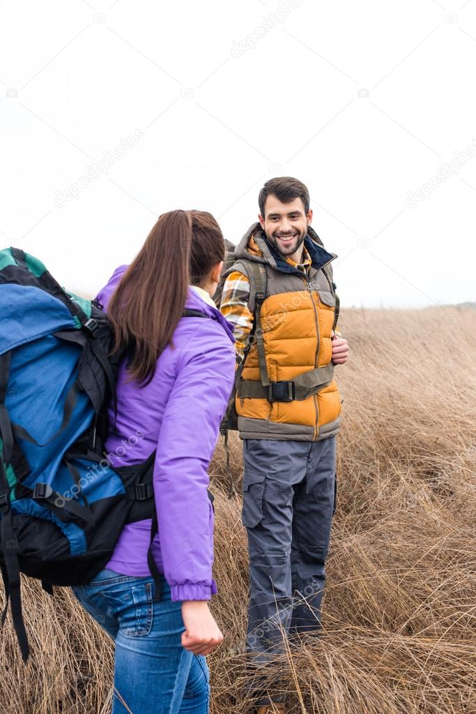 Young backpackers standing in dry grass
