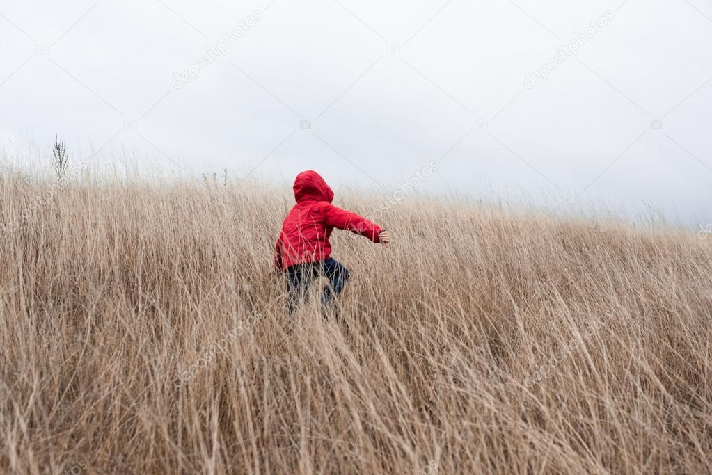 Little boy walking in dry grass 