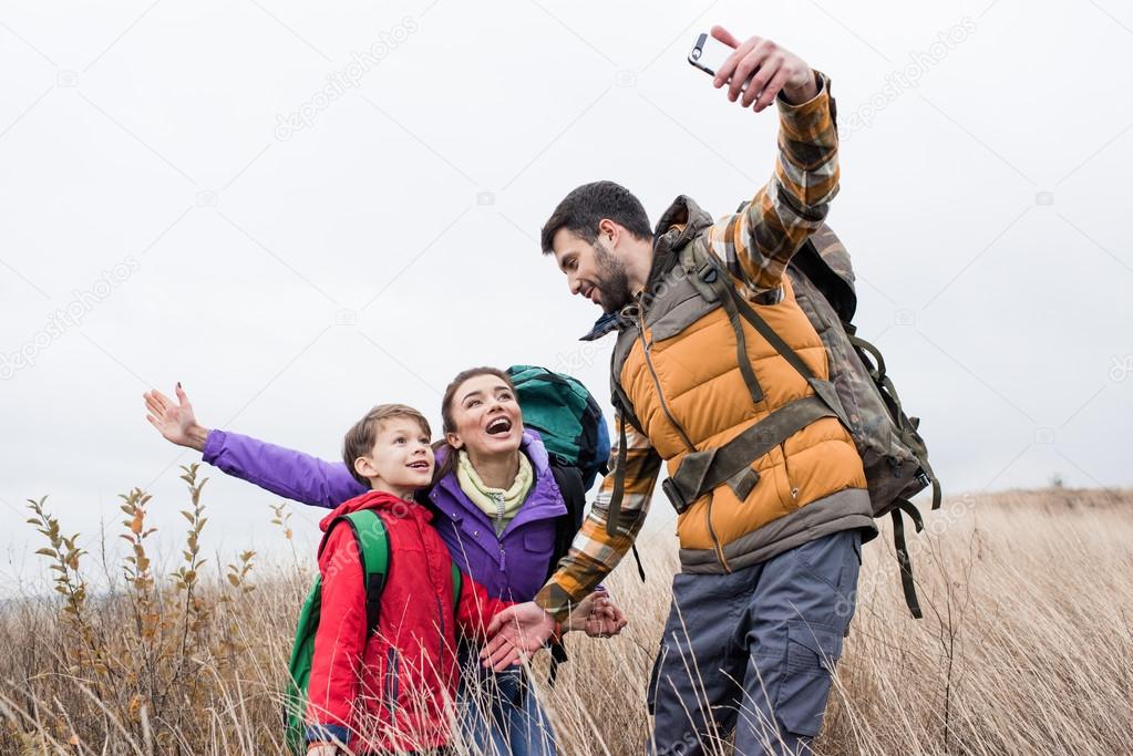 Happy family with backpacks taking selfie