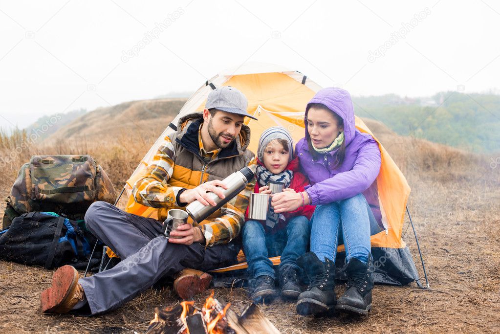 Family drinking tea near burning fire