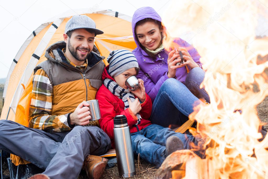 Family drinking tea near burning fire