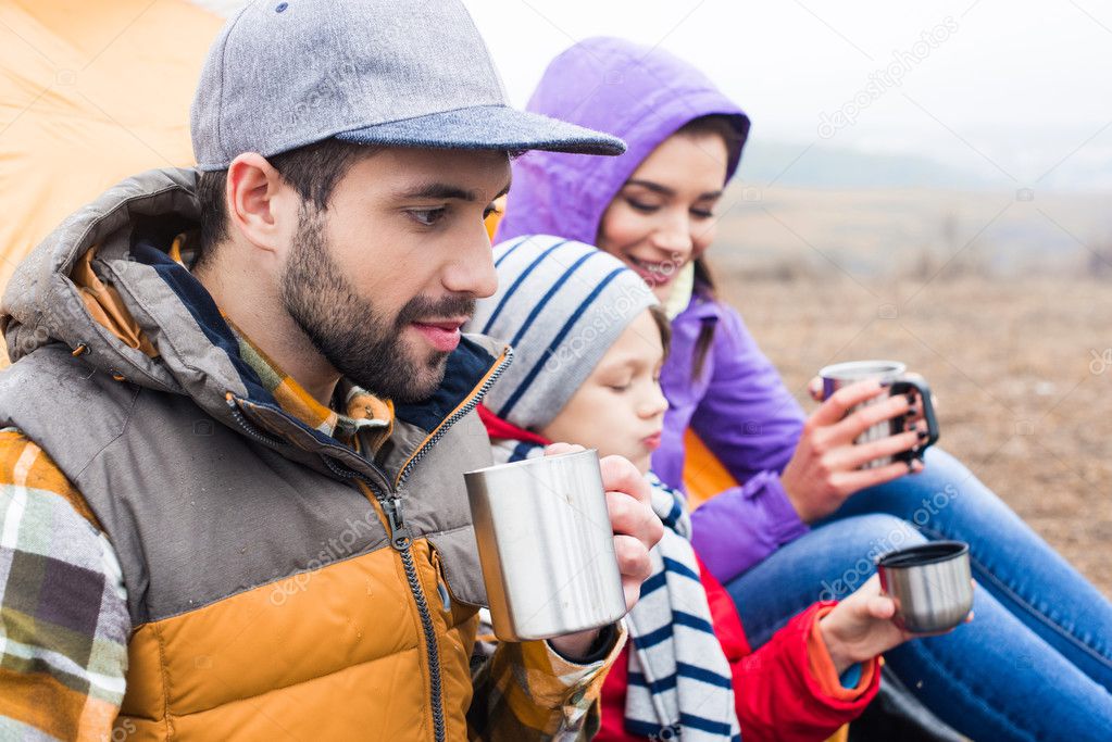 Family drinking tea from metal cups